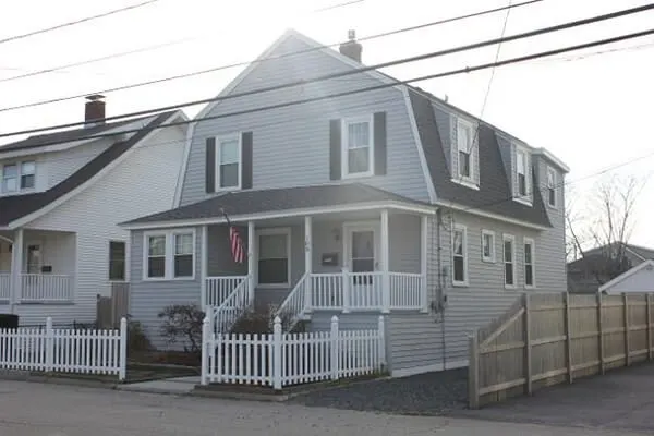 Gambrel home with fresh siding and white picket fence